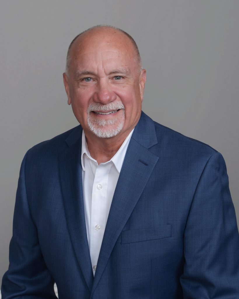 Headshot of man with white goatee, blue sport coat and white shirt