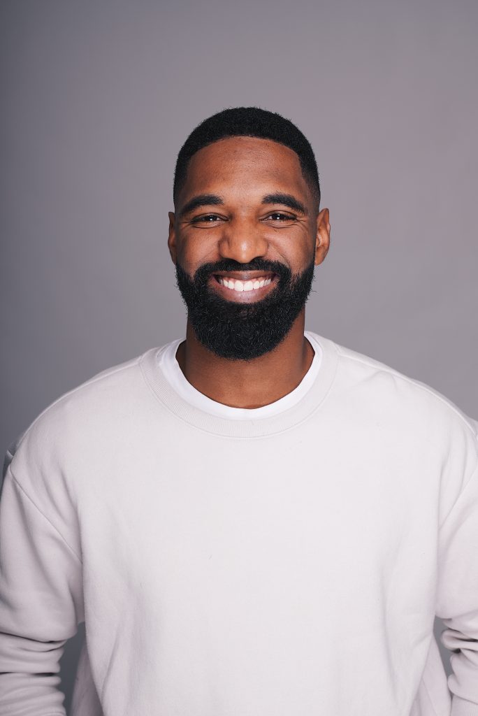 Headshot of man with black hair and beard wearing white long sleeve shirt