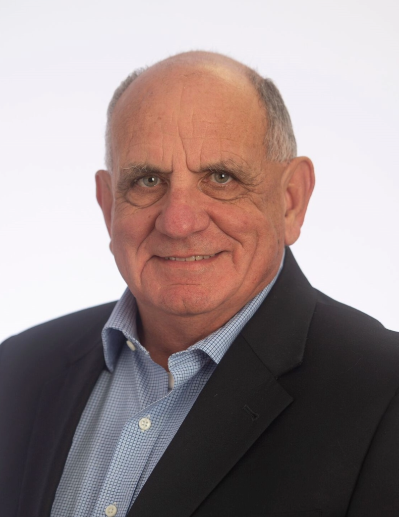 Headhot of man with gray hair, black sport coat and blue and white checkered shirt