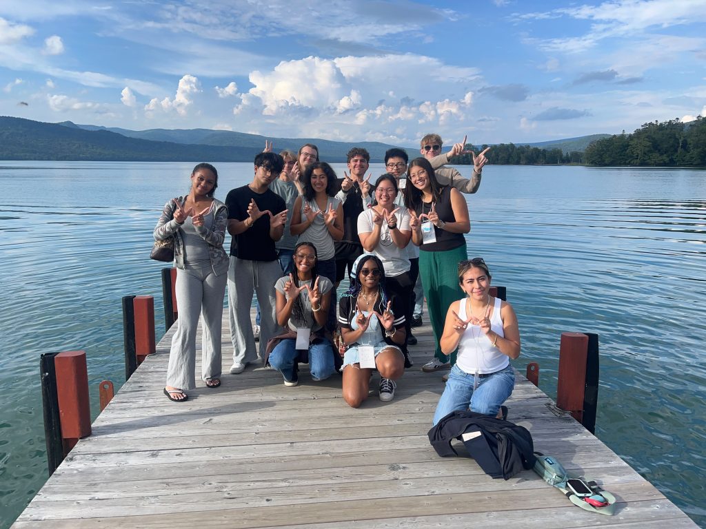A group of students pose for a photo on a pier in a lake