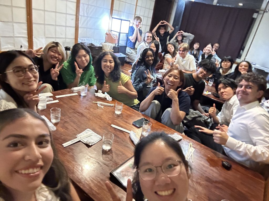 A large group of students smile for a photo while sitting around a dinner table