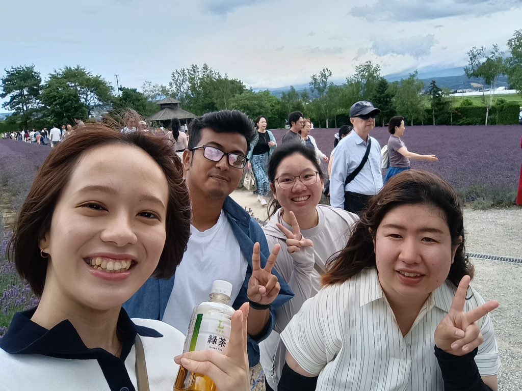 Four people pose for a selfie while walking through lavender fields